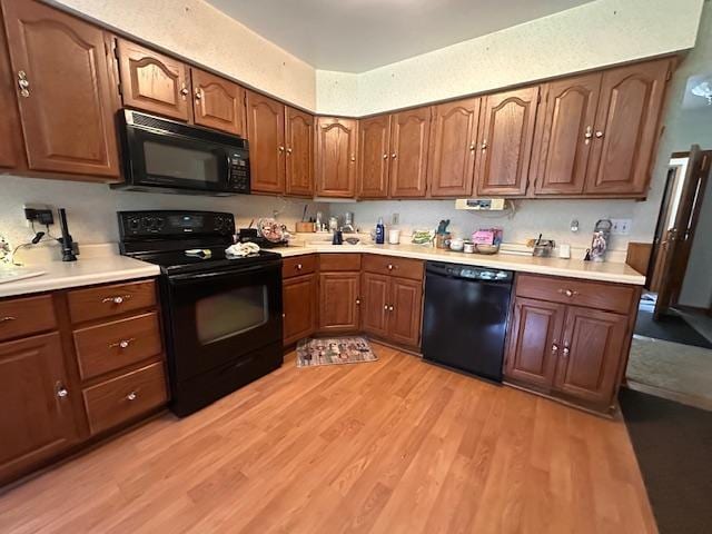 6563 Sandy Ln, Biwabik Twp, MN 55741 - kitchen with black appliances, light wood finished floors, light countertops, and brown cabinetry