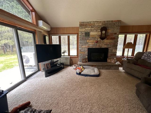 6563 Sandy Ln, Biwabik Twp, MN 55741 - living area featuring an AC wall unit, carpet flooring, a fireplace, plenty of natural light, and vaulted ceiling
