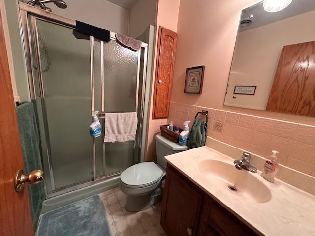 6563 Sandy Ln, Biwabik Twp, MN 55741 - full bathroom with toilet, a stall shower, vanity, and tile walls