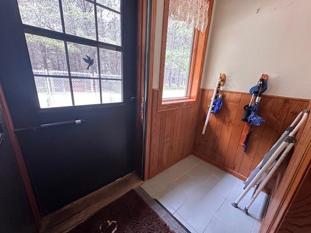6563 Sandy Ln, Biwabik Twp, MN 55741 - doorway with wainscoting, wooden walls, and light tile patterned floors