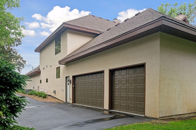 1910 Shoreline Dr, Orono, MN 55391 - view of side of property featuring stucco siding, roof with shingles, and a garage