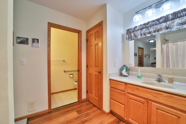909 Lilac Ln, Little Falls, MN 56345 - bathroom featuring toilet, wood finished floors, vanity, and baseboards