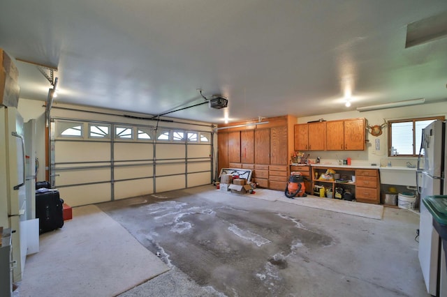 909 Lilac Ln, Little Falls, MN 56345 - garage featuring freestanding refrigerator, a garage door opener, a workshop area, and a sink