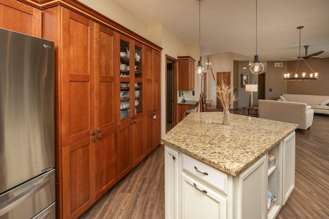 2373 Tee Time Rd SE, Rochester, MN 55904 - kitchen featuring freestanding refrigerator, dark wood-type flooring, a center island, glass insert cabinets, and light stone counters