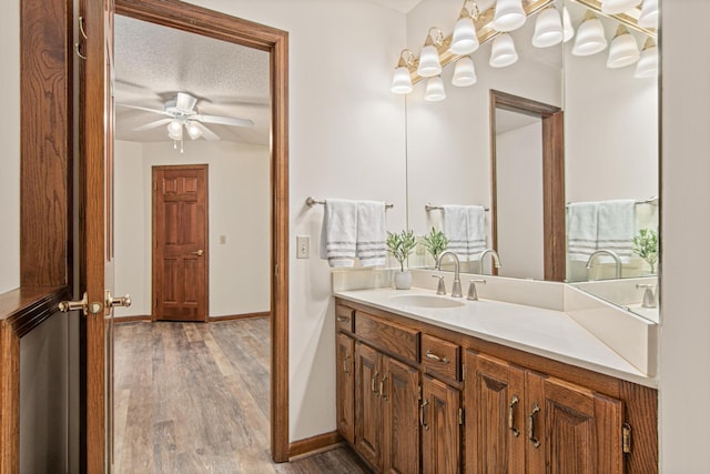 1263 Silverthorn Dr, Shoreview, MN 55126 - bathroom featuring wood finished floors, vanity, baseboards, a ceiling fan, and a textured ceiling