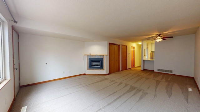 1904 Greenview Pl SW, Rochester, MN 55902 - unfurnished living room with light carpet, a tiled fireplace, a ceiling fan, and baseboards