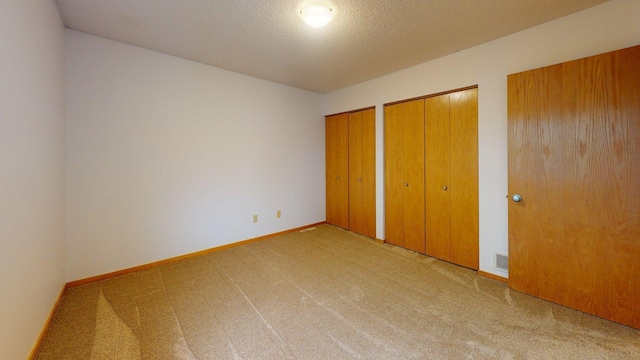 1904 Greenview Pl SW, Rochester, MN 55902 - unfurnished bedroom featuring multiple closets, carpet, baseboards, and a textured ceiling