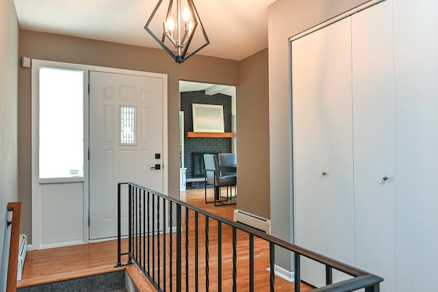 4020 Orleans Ln N, Plymouth, MN 55441 - foyer entrance with wood finished floors, a baseboard radiator, a chandelier, and a brick fireplace