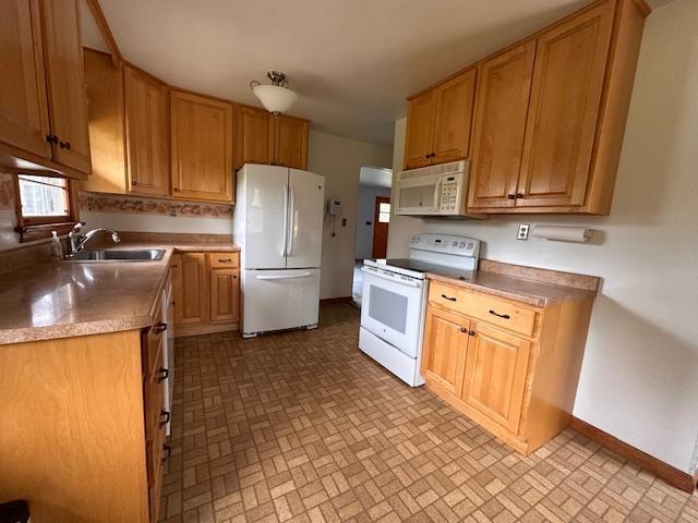 5960 Evergreen Rd, Biwabik Twp, MN 55705 - kitchen with white appliances, a sink, baseboards, light countertops, and brick patterned floors