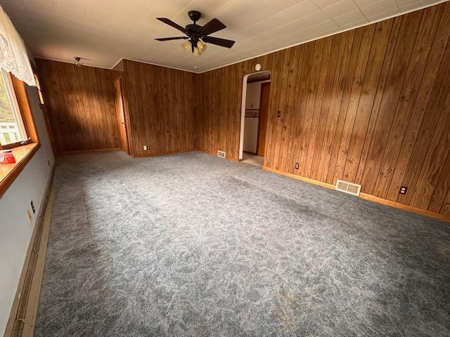 5960 Evergreen Rd, Biwabik Twp, MN 55705 - empty room featuring ceiling fan, wooden walls, carpet, arched walkways, and baseboards