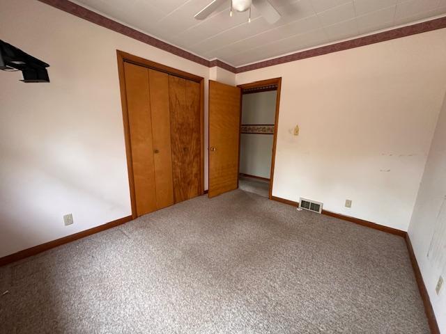 5960 Evergreen Rd, Biwabik Twp, MN 55705 - unfurnished bedroom featuring carpet, a closet, baseboards, a ceiling fan, and ornamental molding