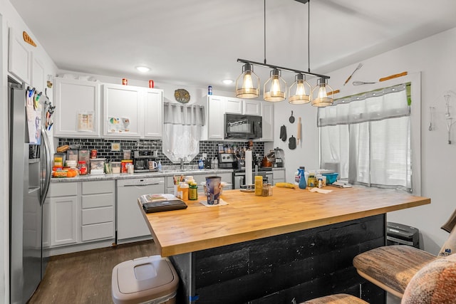 820 6th St, Montevideo, MN 56265 - kitchen with appliances with stainless steel finishes, butcher block counters, backsplash, dark wood-style floors, and white cabinetry