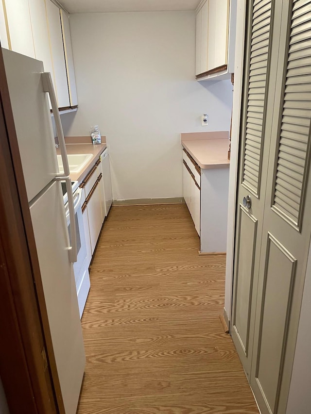 4030 15th Ave S Unit 8C, Minneapolis, MN 55407 - kitchen with freestanding refrigerator, light wood-type flooring, white cabinets, and light countertops