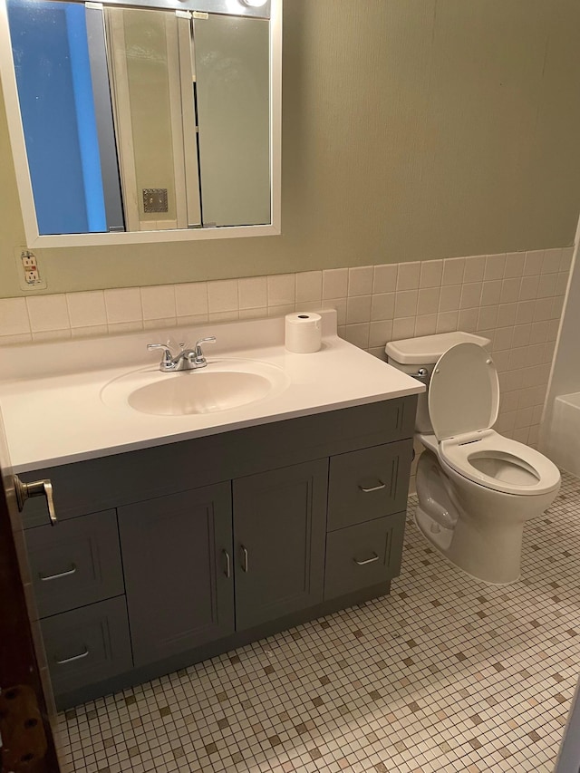 4030 15th Ave S Unit 8C, Minneapolis, MN 55407 - bathroom with vanity, toilet, wainscoting, tile walls, and tile patterned flooring
