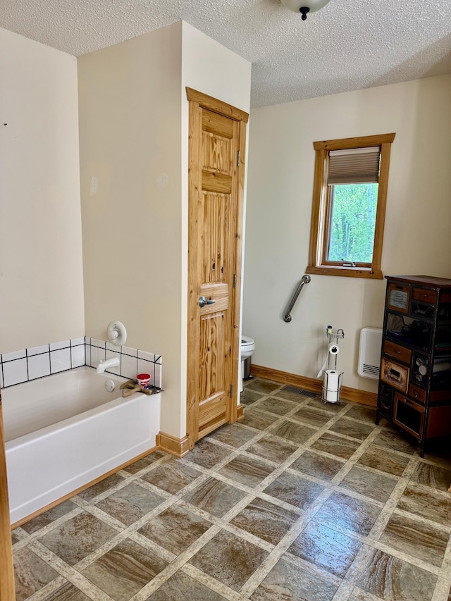 11777 State Highway 11 SE, Baudette, MN 56623 - bathroom featuring a garden tub, toilet, a textured ceiling, and baseboards