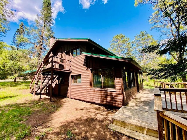 6974 Bankers Dr, Minong, WI 54859 - view of side of property featuring faux log siding, a deck, stairway, and a chimney