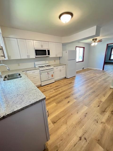 1269 Margaret St, Saint Paul, MN 55106 - kitchen featuring white appliances, a sink, white cabinets, light wood-style flooring, and baseboards