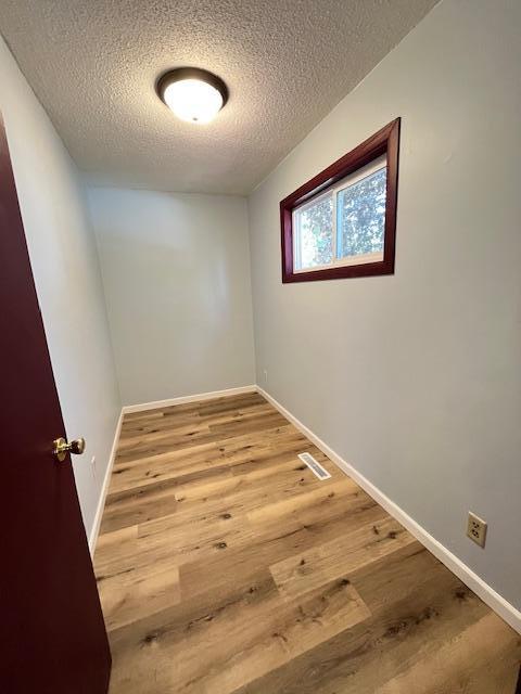 1269 Margaret St, Saint Paul, MN 55106 - empty room featuring a textured ceiling, wood finished floors, and baseboards