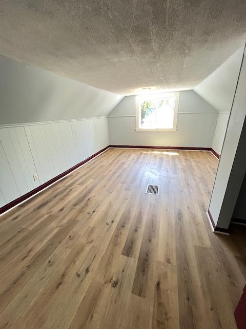 1269 Margaret St, Saint Paul, MN 55106 - additional living space with wood finished floors, vaulted ceiling, and a textured ceiling