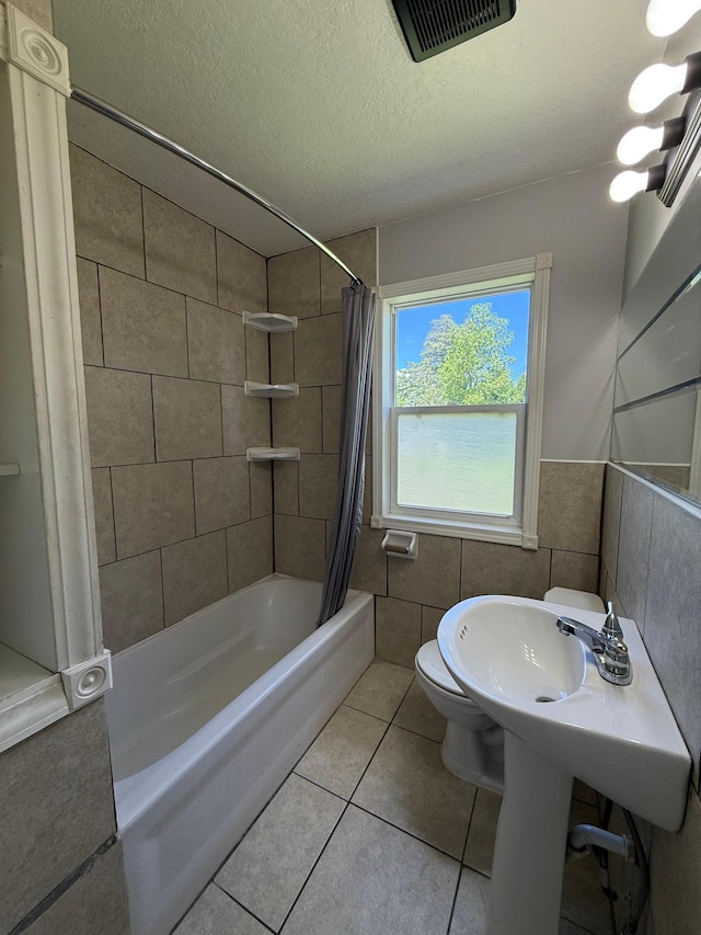 446 Darwin St, Litchfield, MN 55355 - full bath featuring shower / tub combo with curtain, tile walls, toilet, tile patterned floors, and a textured ceiling