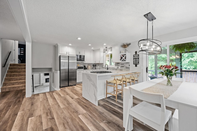 7190 Annapolis Cir, Maple Grove, MN 55311 - kitchen featuring stainless steel appliances, a peninsula, a textured ceiling, tasteful backsplash, and light wood-type flooring
