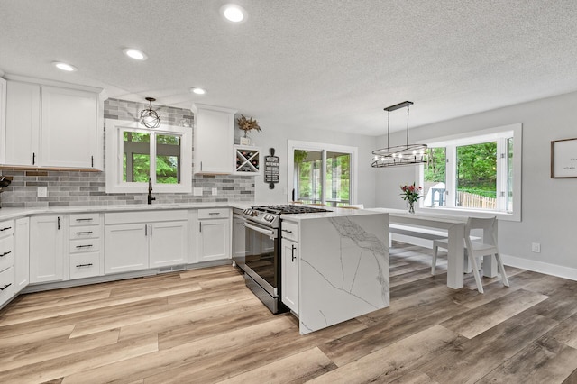 7190 Annapolis Cir, Maple Grove, MN 55311 - kitchen with stainless steel range with gas stovetop, a sink, a textured ceiling, a peninsula, and white cabinetry