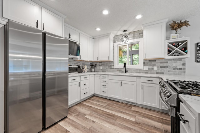 7190 Annapolis Cir, Maple Grove, MN 55311 - kitchen featuring appliances with stainless steel finishes, a sink, white cabinetry, a textured ceiling, and tasteful backsplash