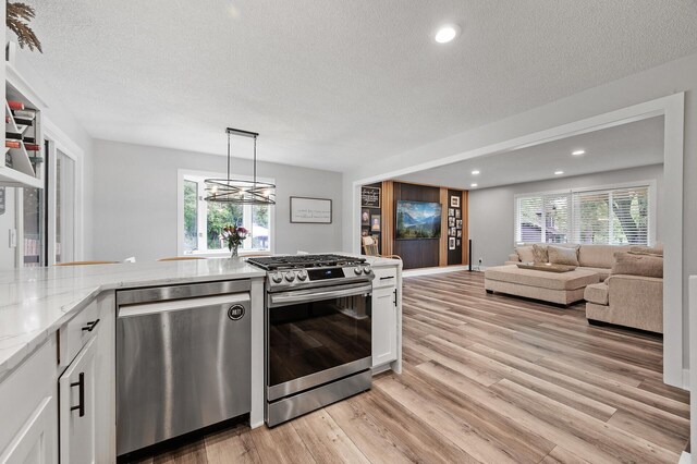 7190 Annapolis Cir, Maple Grove, MN 55311 - kitchen featuring appliances with stainless steel finishes, a textured ceiling, white cabinetry, light wood-type flooring, and light stone countertops