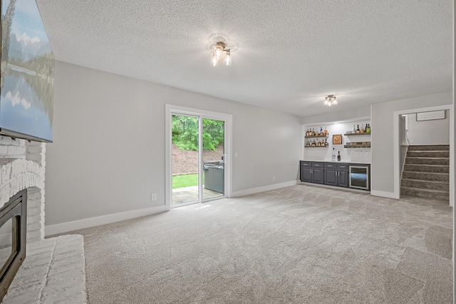 7190 Annapolis Cir, Maple Grove, MN 55311 - unfurnished living room featuring bar area, a glass covered fireplace, light carpet, a textured ceiling, and baseboards
