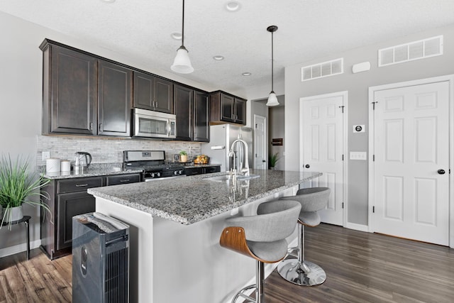 6980 Archer Trl, Inver Grove Heights, MN 55077 - kitchen featuring appliances with stainless steel finishes, a sink, dark wood-style floors, a breakfast bar area, and tasteful backsplash