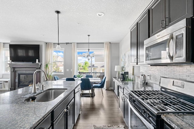 6980 Archer Trl, Inver Grove Heights, MN 55077 - kitchen featuring appliances with stainless steel finishes, a sink, a glass covered fireplace, a textured ceiling, and tasteful backsplash