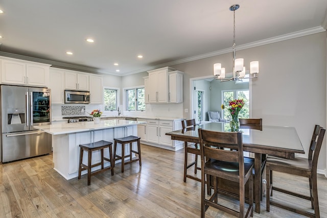 3877 Fairway Dr, Woodbury, MN 55125 - kitchen featuring stainless steel appliances, a chandelier, crown molding, a kitchen island, and a kitchen breakfast bar