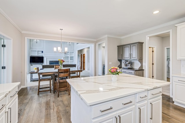 3877 Fairway Dr, Woodbury, MN 55125 - kitchen featuring light wood-style flooring, ornamental molding, a center island, decorative light fixtures, and light stone countertops