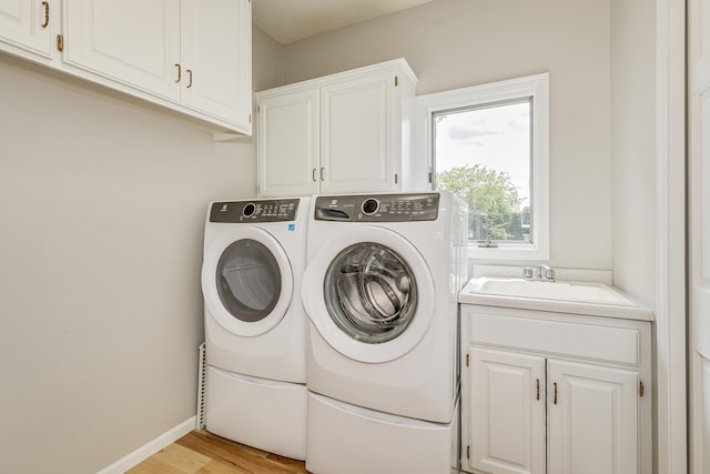 3877 Fairway Dr, Woodbury, MN 55125 - laundry room featuring cabinet space, washer and clothes dryer, light wood-style floors, and baseboards