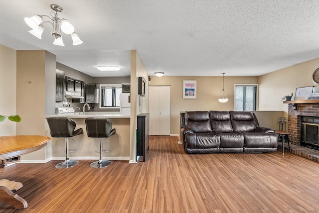 445 Shelard Pkwy Unit 204, Saint Louis Park, MN 55426 - living room featuring light wood-type flooring, a fireplace, a chandelier, a textured ceiling, and baseboards