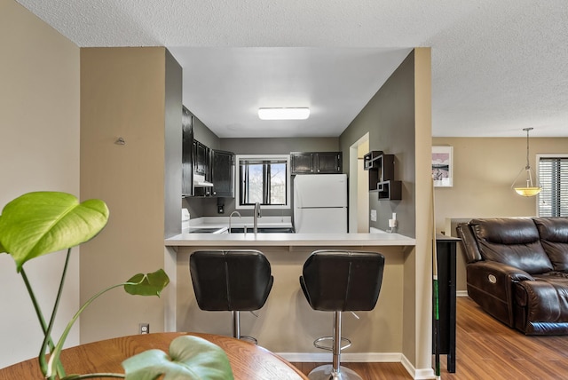 445 Shelard Pkwy Unit 204, Saint Louis Park, MN 55426 - kitchen with freestanding refrigerator, wood finished floors, a kitchen breakfast bar, light countertops, and a peninsula