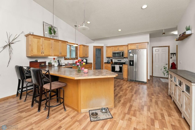 4465 53rd St S, Fargo, ND 58104 - kitchen with stainless steel appliances, a peninsula, light wood finished floors, high vaulted ceiling, and a textured ceiling