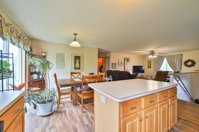 9095 Twins St, Brainerd, MN 56401 - kitchen with light wood-type flooring, light countertops, a kitchen island, ceiling fan, and pendant lighting