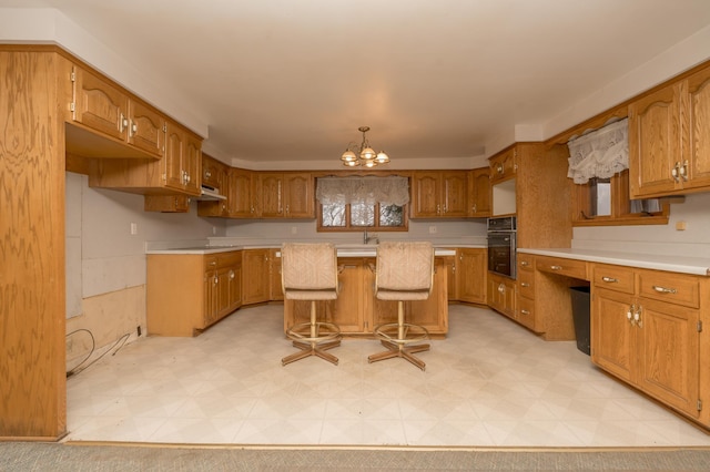 6950 270th St, New Prague, MN 56071 - kitchen with black oven, brown cabinets, light countertops, and a center island