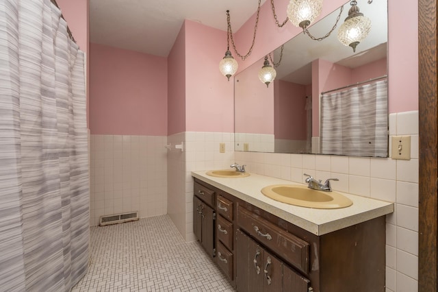 6950 270th St, New Prague, MN 56071 - bathroom featuring tile walls, double vanity, and a wainscoted wall