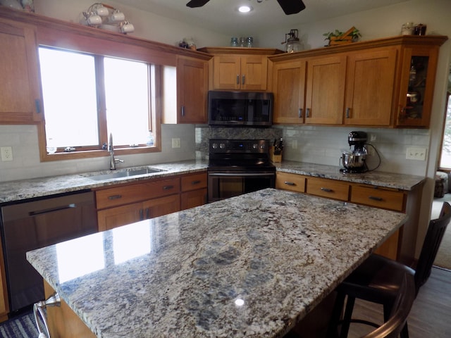534 200th St, Cedar Twp, MN 56176 - kitchen with stainless steel appliances, a sink, brown cabinets, a ceiling fan, and light stone countertops