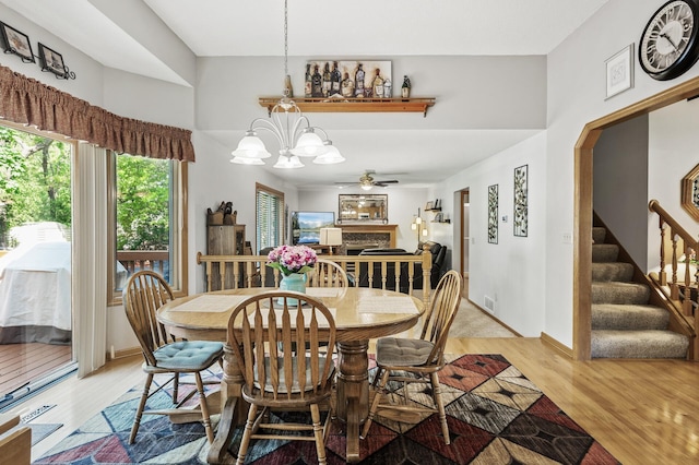 15144 Zilla St NW, Andover, MN 55304 - dining area with light wood finished floors, a chandelier, a ceiling fan, stairway, and a fireplace