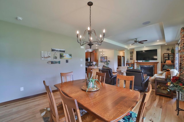 23369 330th St, Sebeka, MN 56477 - dining area featuring ceiling fan, light wood-style floors, a tray ceiling, and a fireplace