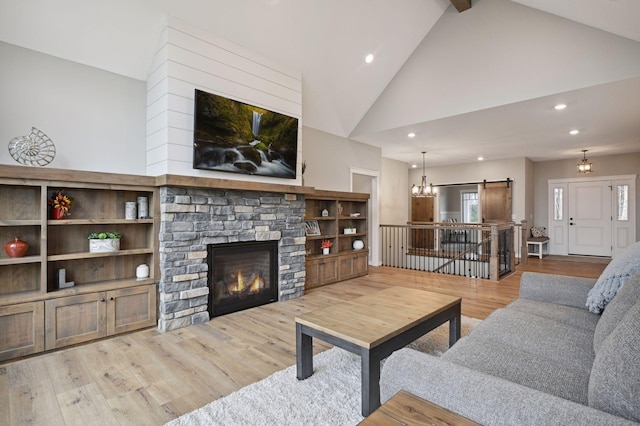 18022 Urbank St NE, Ham Lake, MN 55304 - living room with a barn door, high vaulted ceiling, a stone fireplace, recessed lighting, and wood finished floors