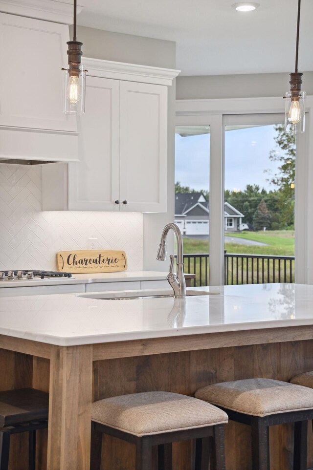 18022 Urbank St NE, Ham Lake, MN 55304 - kitchen with white cabinetry, tasteful backsplash, decorative light fixtures, light stone counters, and a breakfast bar area