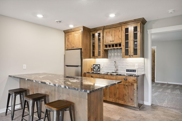 18022 Urbank St NE, Ham Lake, MN 55304 - kitchen with freestanding refrigerator, a sink, a peninsula, dark stone counters, and a kitchen breakfast bar