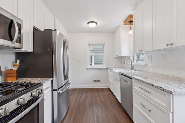 2904 Jersey Ave S, Saint Louis Park, MN 55426 - kitchen with appliances with stainless steel finishes, dark wood finished floors, tasteful backsplash, white cabinets, and light stone countertops