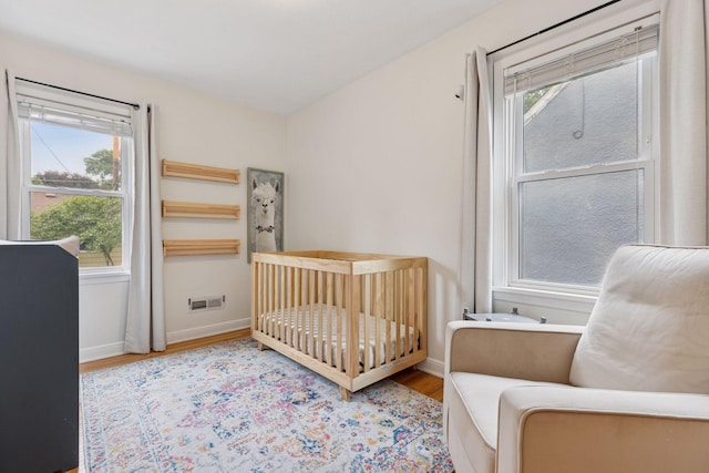 2904 Jersey Ave S, Saint Louis Park, MN 55426 - bedroom featuring wood finished floors, multiple windows, and a crib