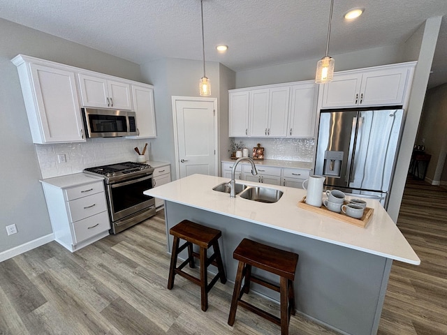 11798 5th St NE, Hanover, MN 55341 - kitchen with stainless steel appliances, a sink, light wood-type flooring, a kitchen breakfast bar, and white cabinetry