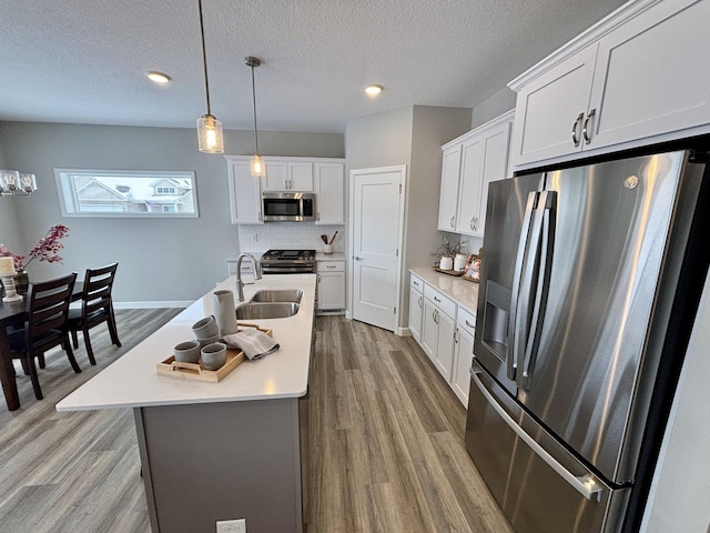 11798 5th St NE, Hanover, MN 55341 - kitchen featuring stainless steel appliances, a sink, light countertops, wood finished floors, and a textured ceiling